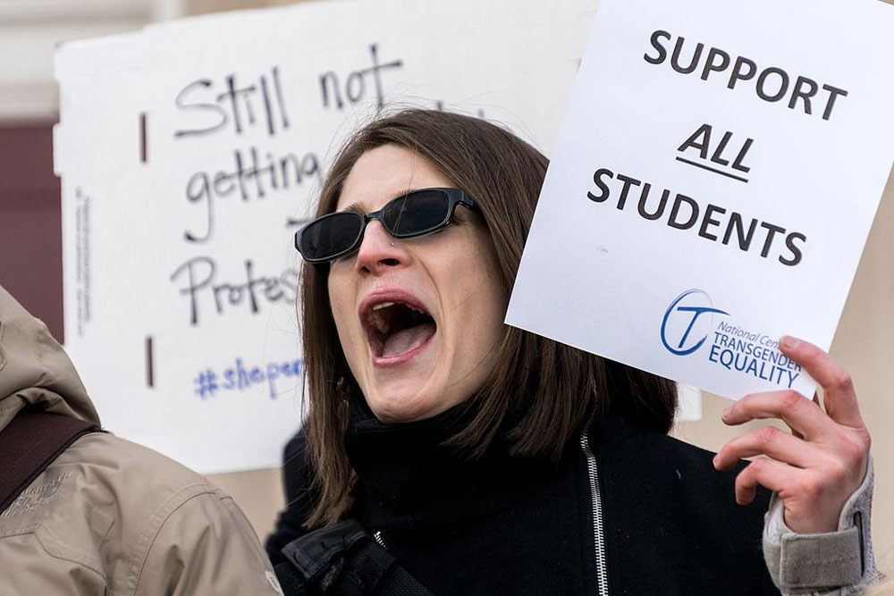A protester with a "Support All Students" sign from the National Center for Transgender Equality.