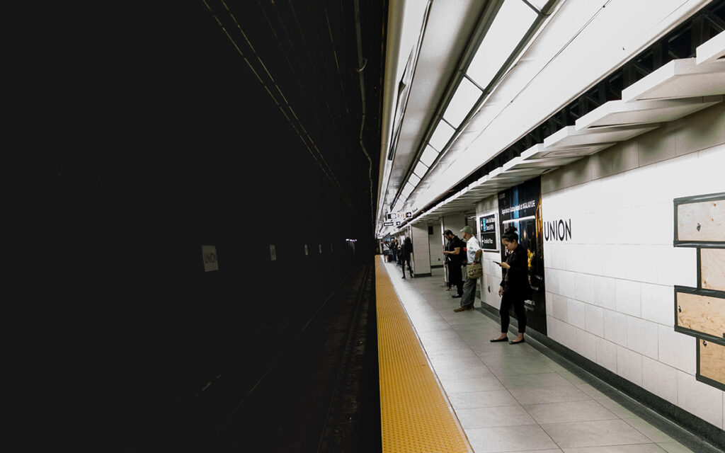 Photo of a train platform, split down the middle into the lit platform and the dark tunnel