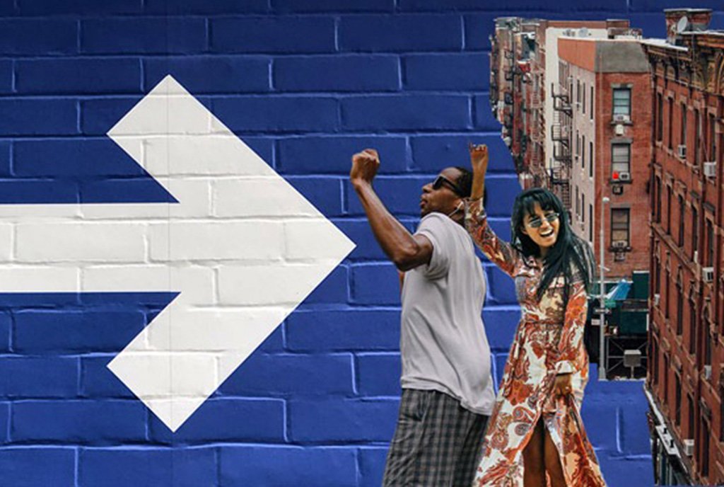 CDFI Image: A white arrow painted on a black brick wall points to city buildings and a man and woman holding their fists in the air.