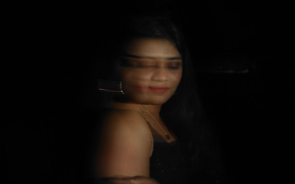 A brown-skinned woman in red lipstick turning towards the camera. She is in motion, indicated by the blurring effect from her movement.