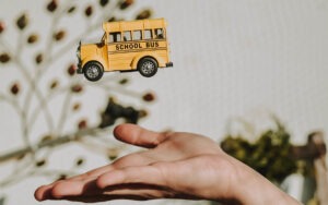 A hand tossing up a toy school bus in the air