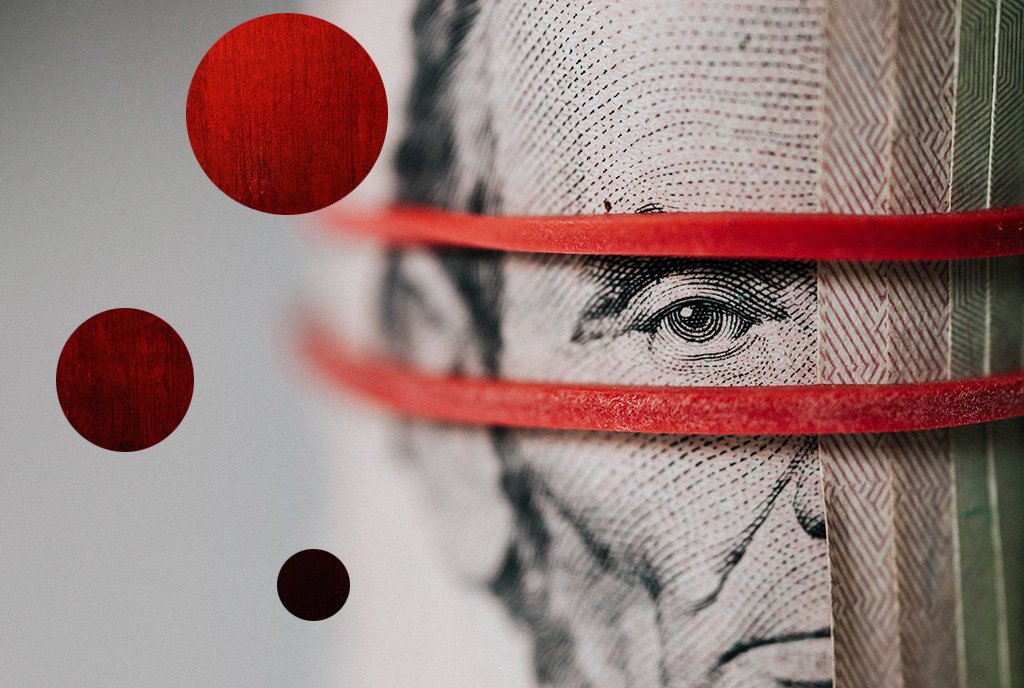 Capitalism Image: Close up of five dollar bill with red lines over Abraham Lincoln's face and red dots on the left.