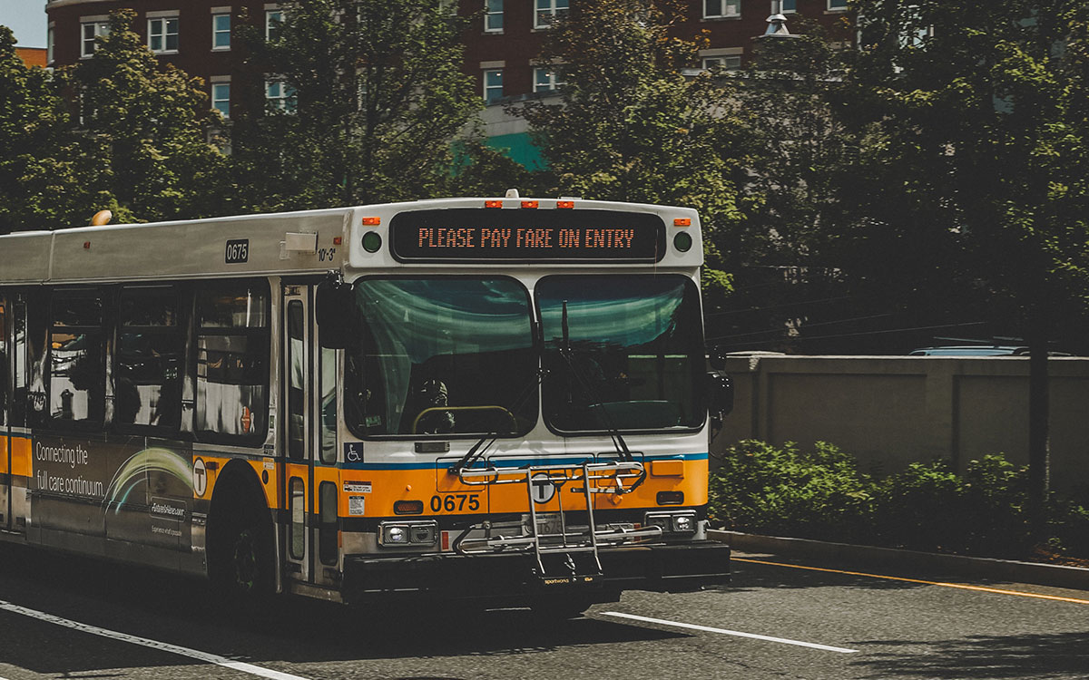 MBTA bus driving down the street. The words “Please pay fare on entry” are displayed in the marquee on the front of the bus