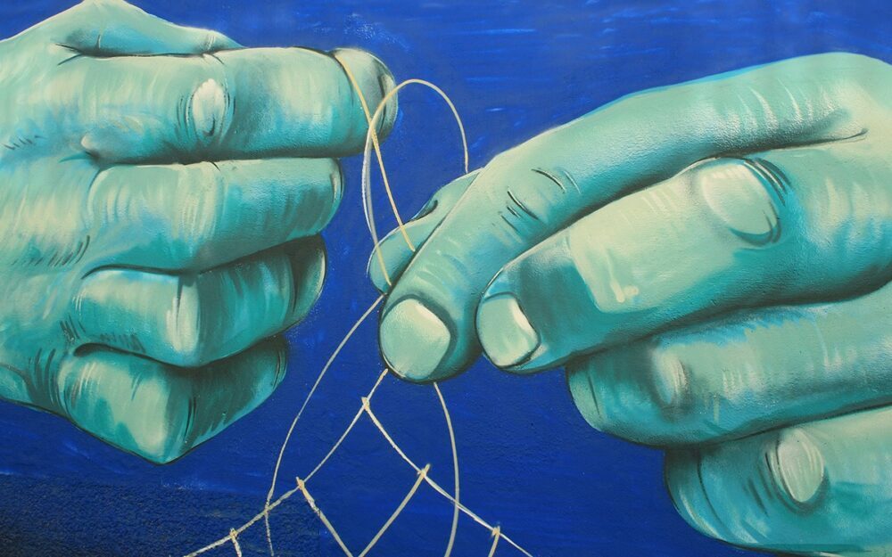 A mural of blue hands tinkering with the ropes of a net