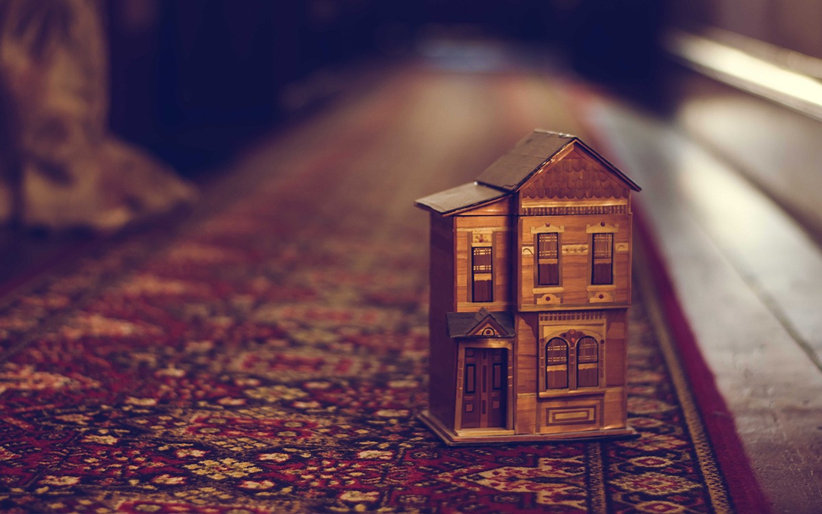 A toy house sitting on a persian rug carpet in a dimly lit room.