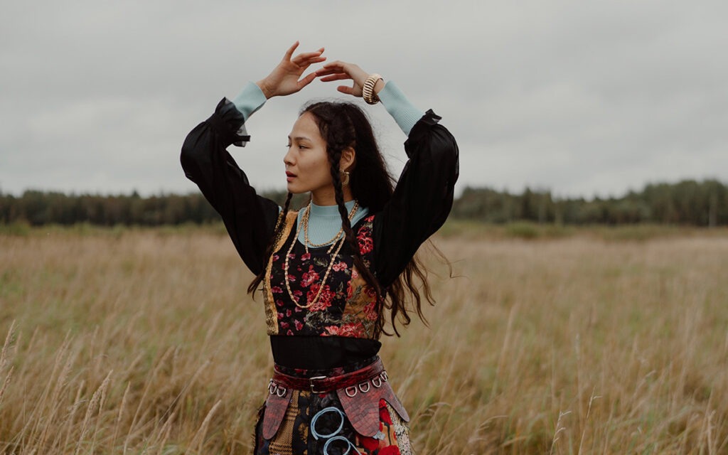 A native woman standing in a wheat field with her hands above her head
