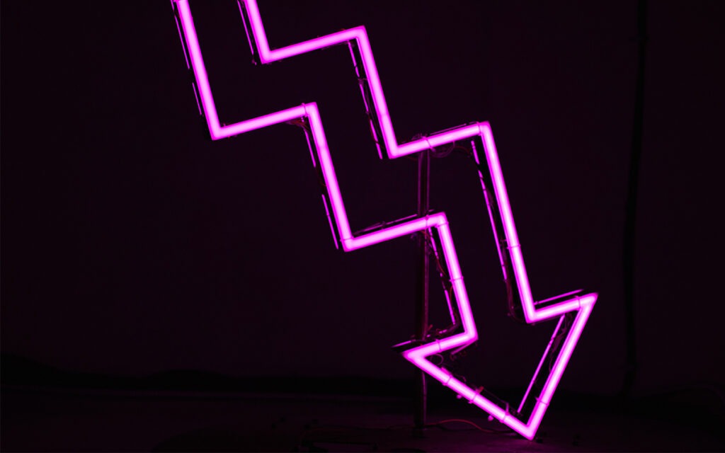 Neon sign of a jagged, chart-style arrow going downwards