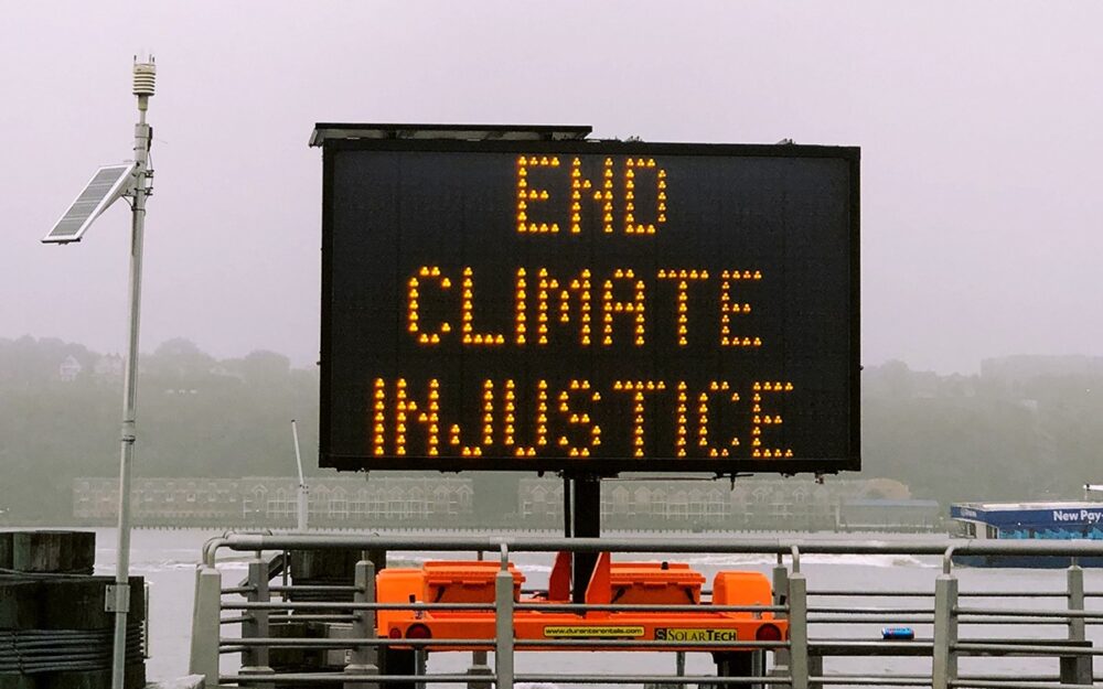A traffic marquee displaying the words, “End Climate Injustice”