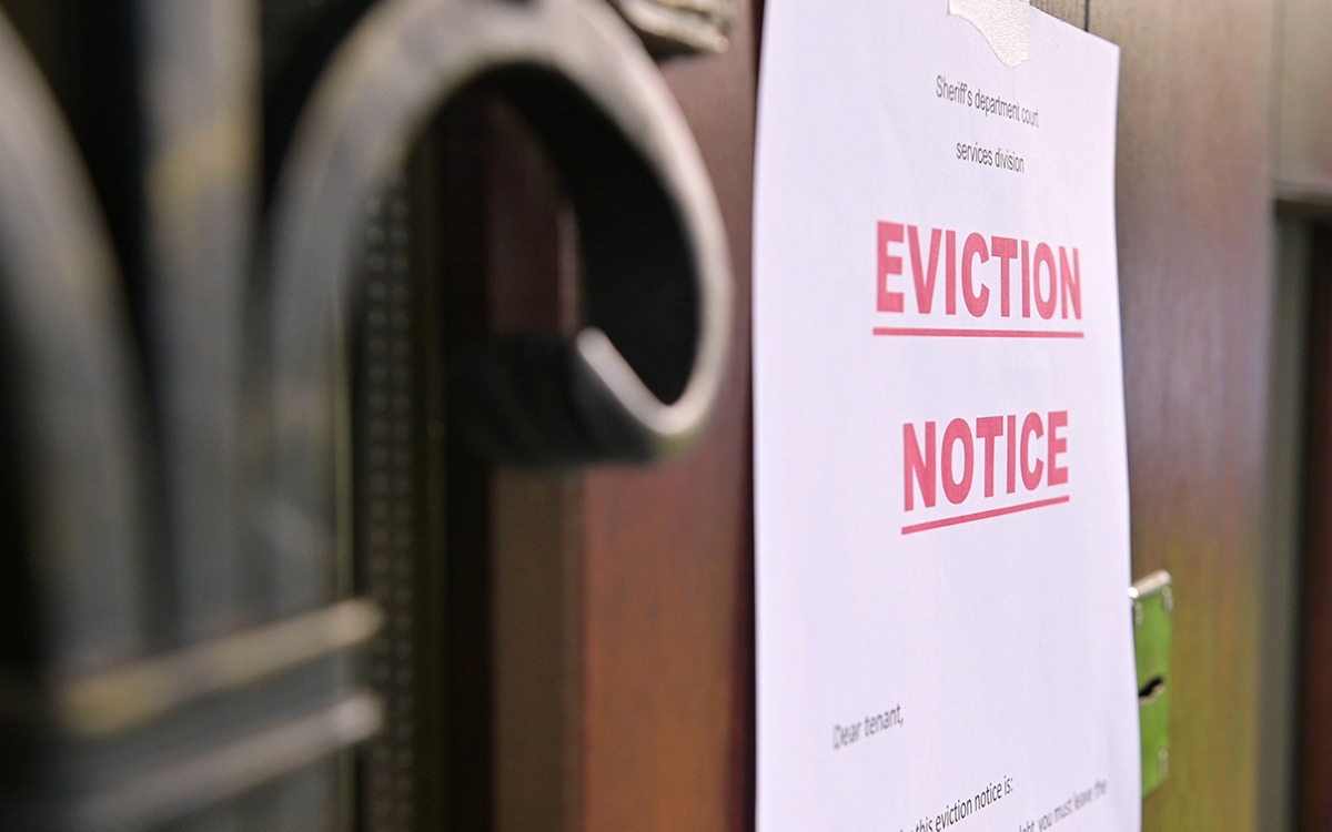 The eviction notice of tenants hangs on a wooden door of a house stock. The words “Eviction Notice” are in big, red letters.
