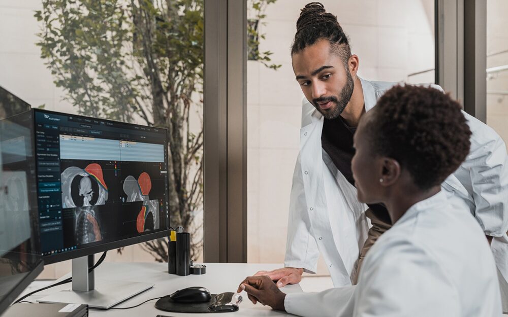 A Black doctor and imaging technician looking at a computer screen with an x-ray of a human torso