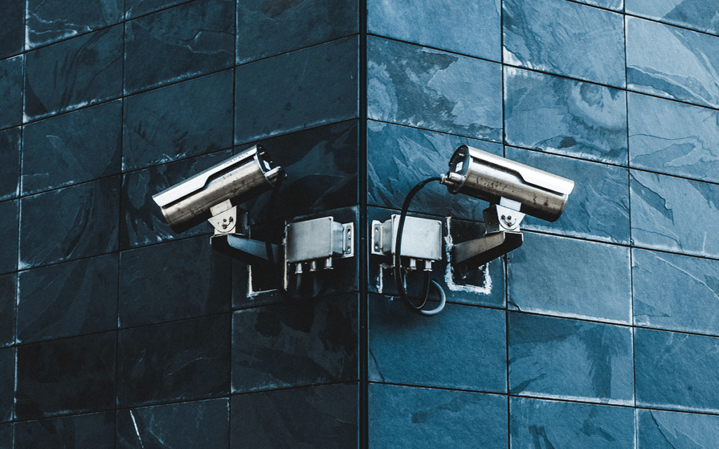 An exterior building corner with a surveillance video camera on each corner.