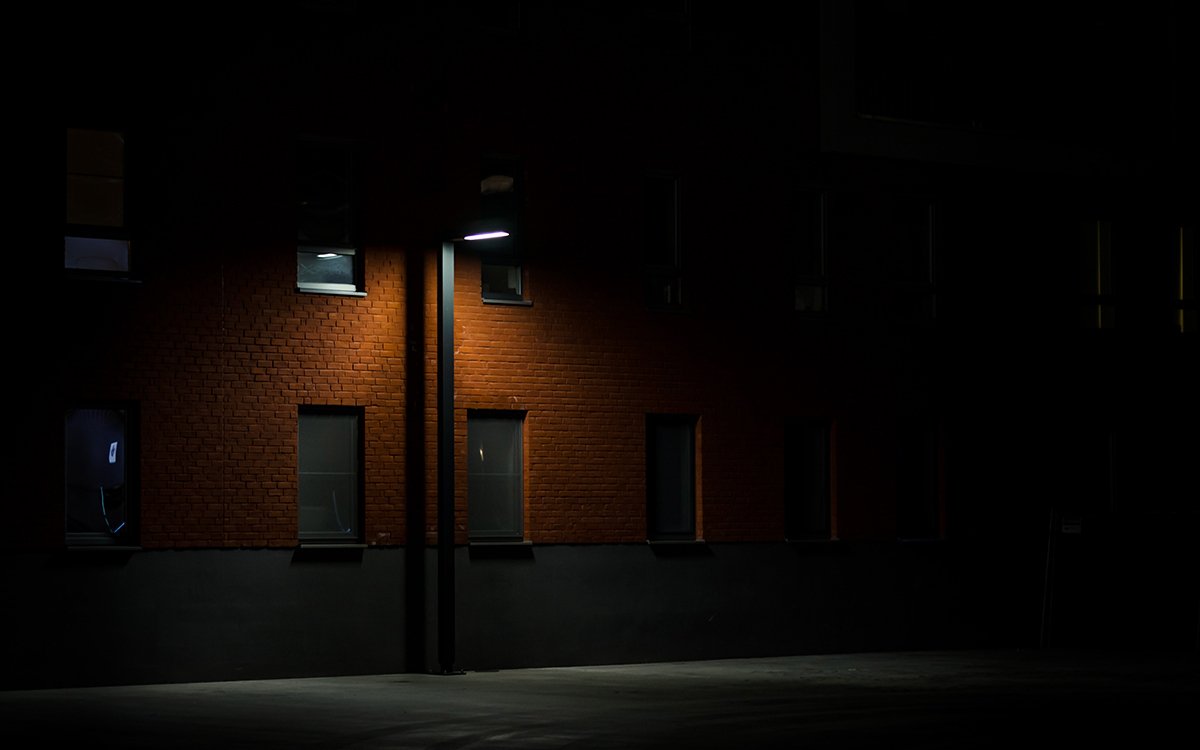 An exterior of a brick, nondescript building on a dimly lit street.