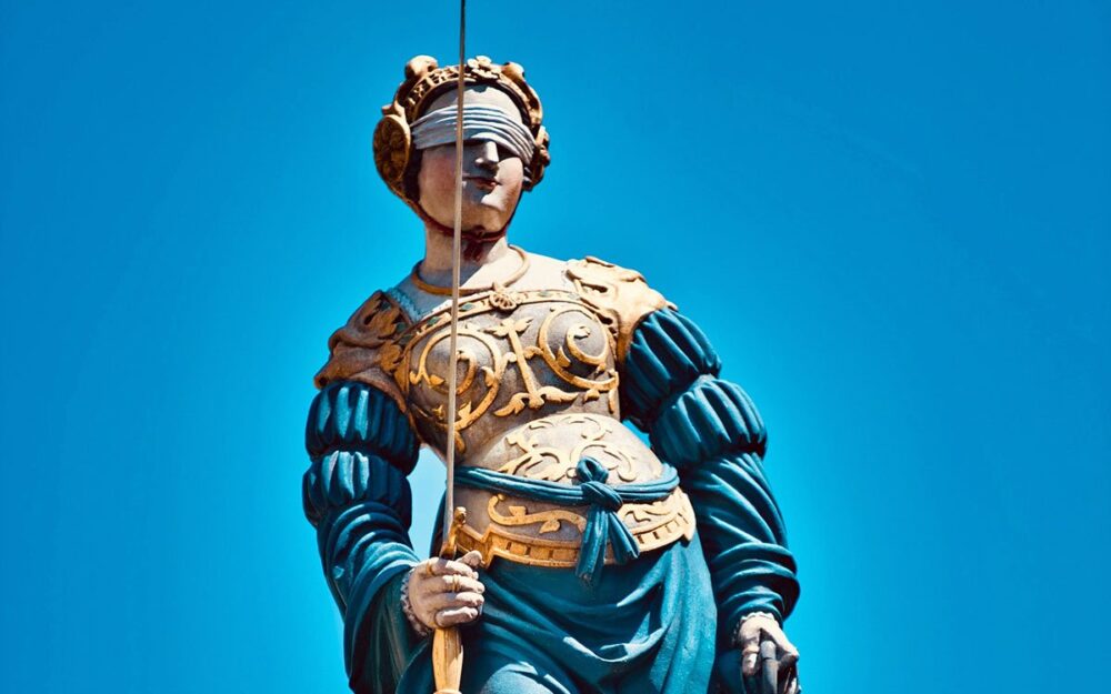 A statue of a blindfolded woman, wearing a bodice of armor and holding a sword.