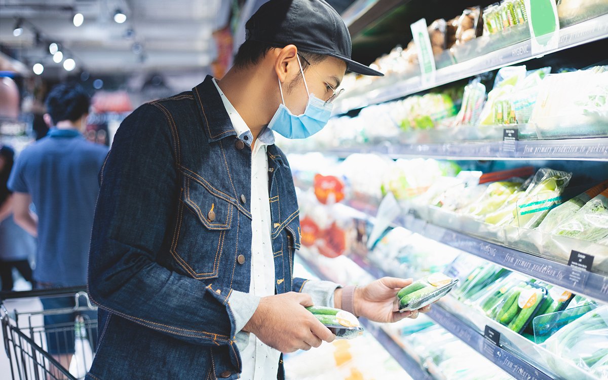 Asian man with face covering shopping for food at a grocery store