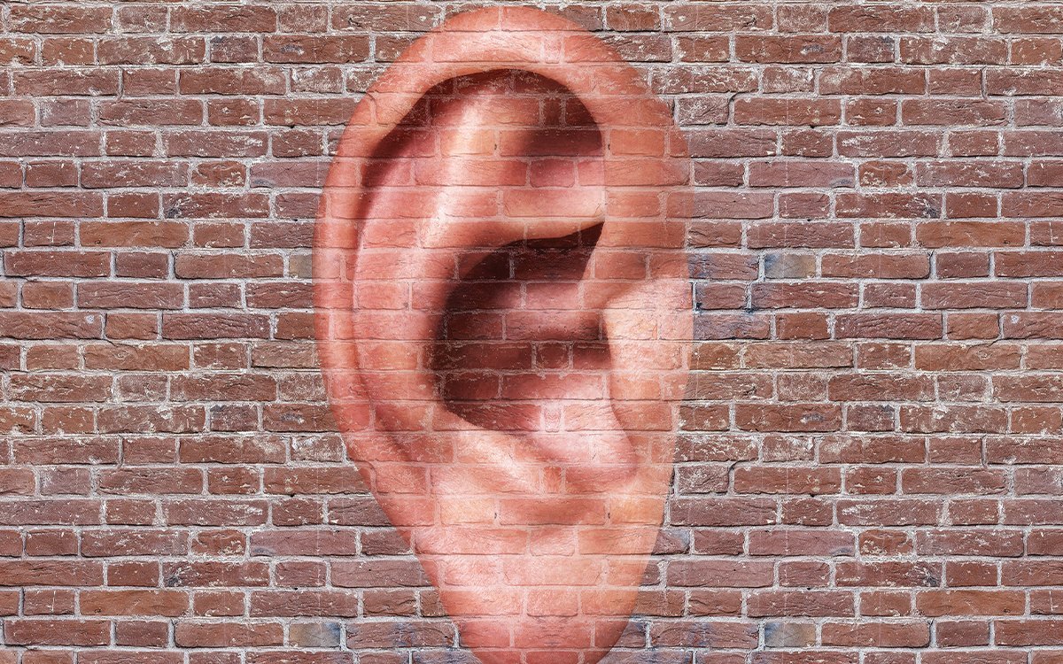 A brick wall with a graffiti image of an ear.