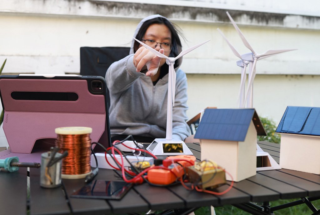 A young student learns and practices with a model solar cell and wind turbine.