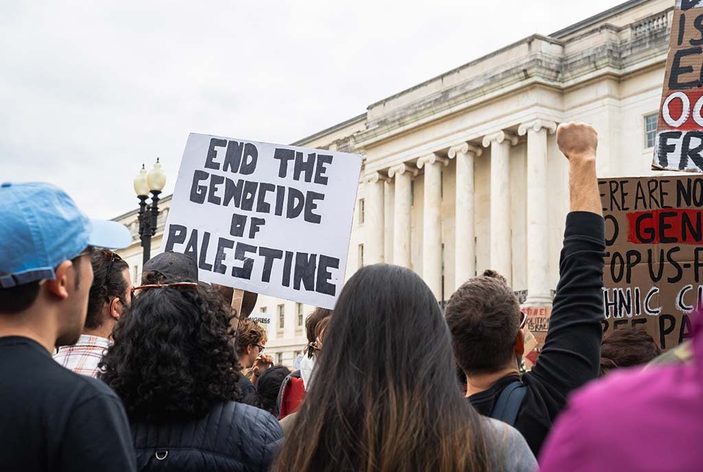 Protestors in Washington D.C., holding up a sign that reads, “End the Genocide of Palestine”