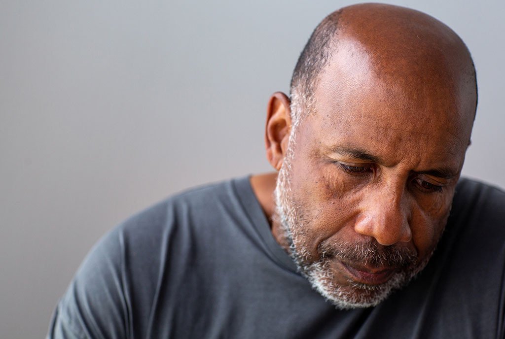 Portrait of an elderly Black man looking sad and away from the camera.