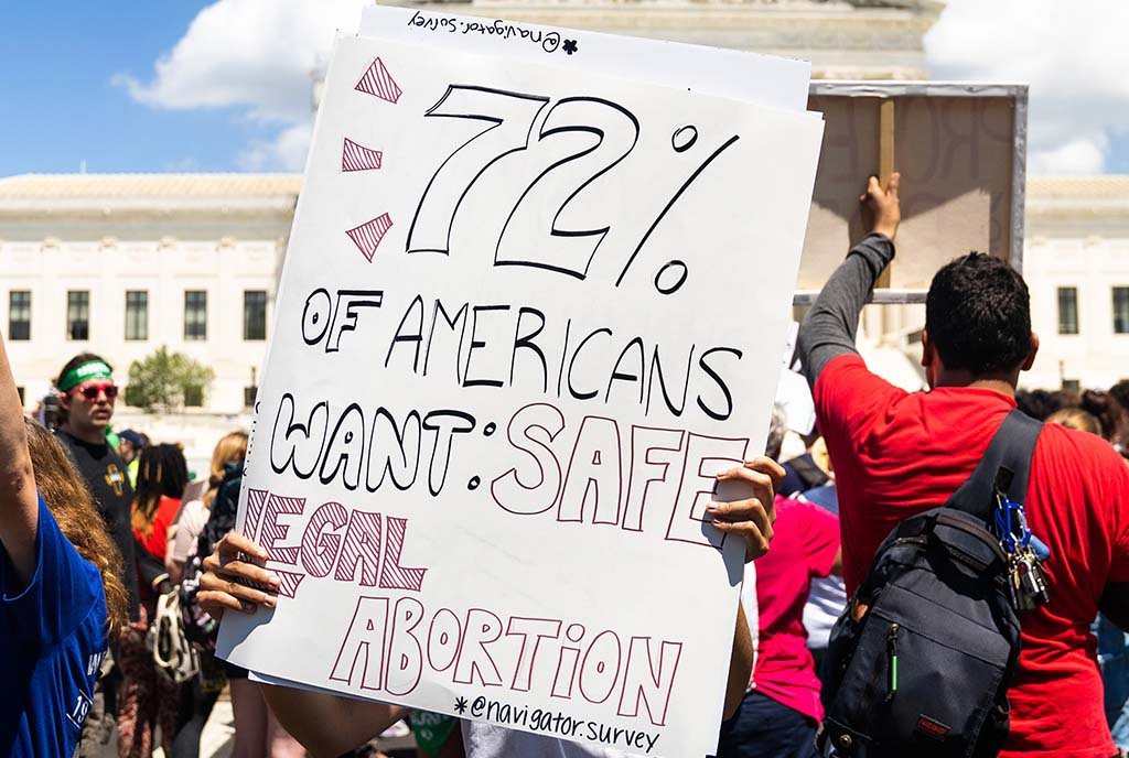 A person at a protest holding a handmade sign that reads, “72% of Americans want safe, legal abortion”