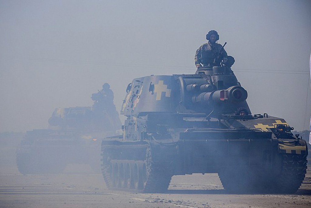 A photo of a Akatsiya Ukrainian Armed Forces tank creeping forward in a haze of gray smoke emissions.