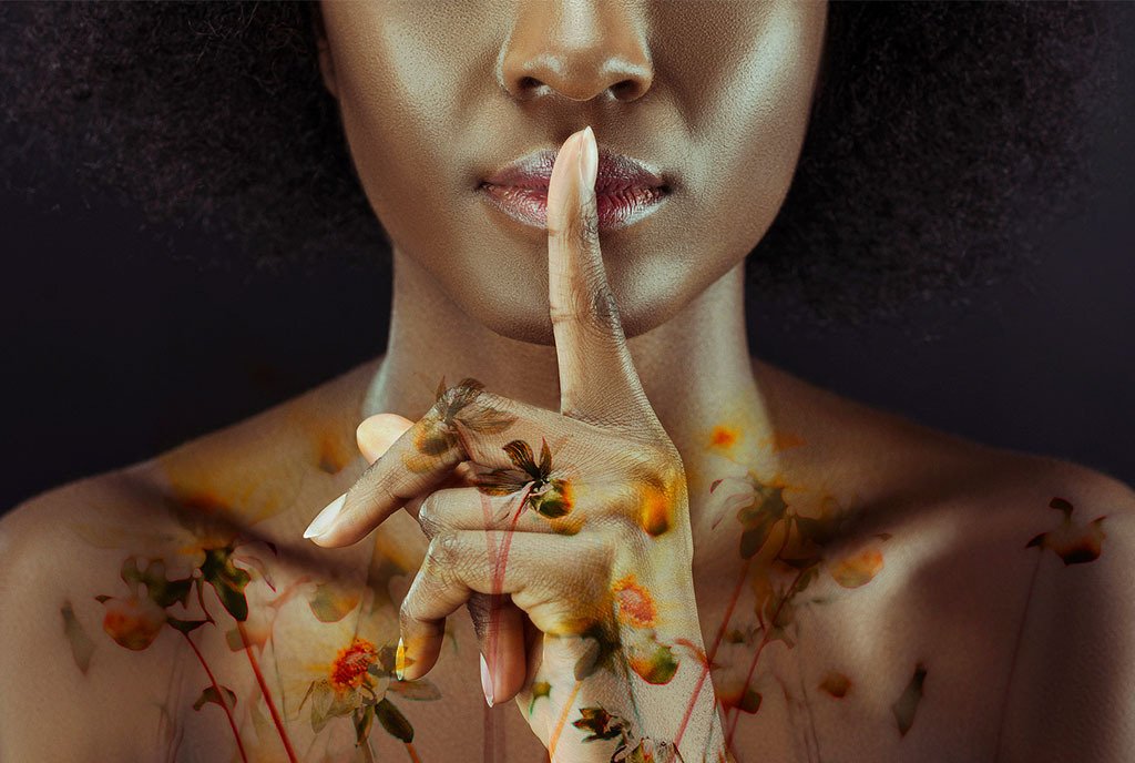 A Black woman holding her fingers to her lips in a quieting gesture, with lemon flowers superimposed on her chest.