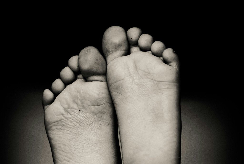 A Black and White photo of the soles of a person’s feet, hoisted into the air.
