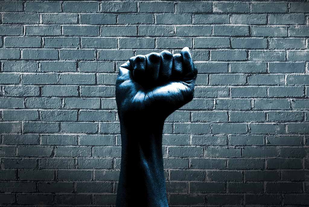 A closed fist, held up against a brick wall
