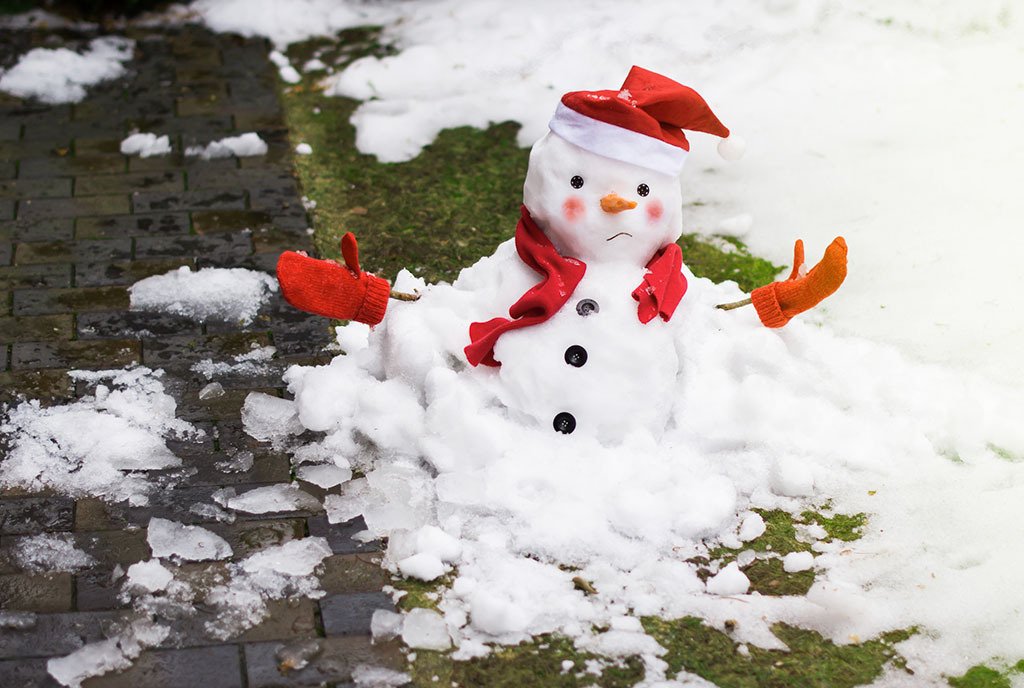 A melting snowman wearing mittens and a red scarf, with an unhappy look on his frozen face.