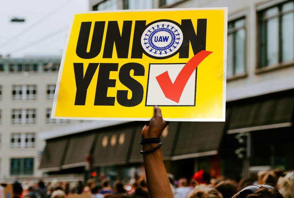 A protestor holding up an UAW sign that reads “Union YES” with a checked checkbox next to the yes.