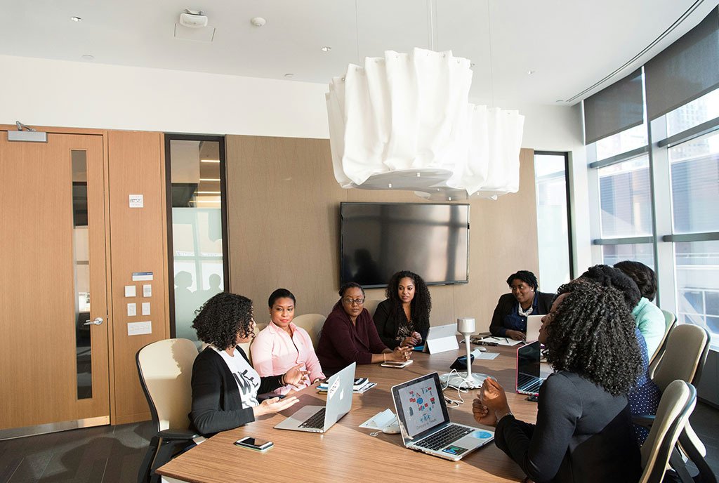 A group of Black woman sitting together with computers and talking.