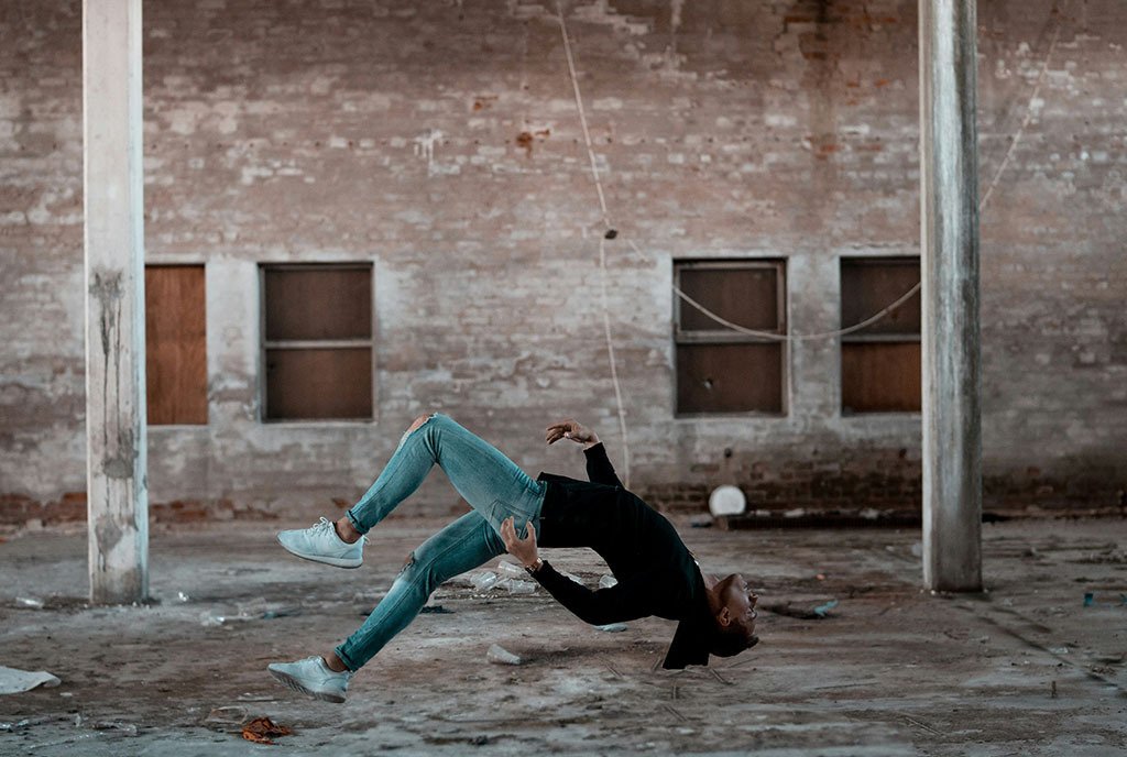 A person mid-air doing a backflip in a warehouse.