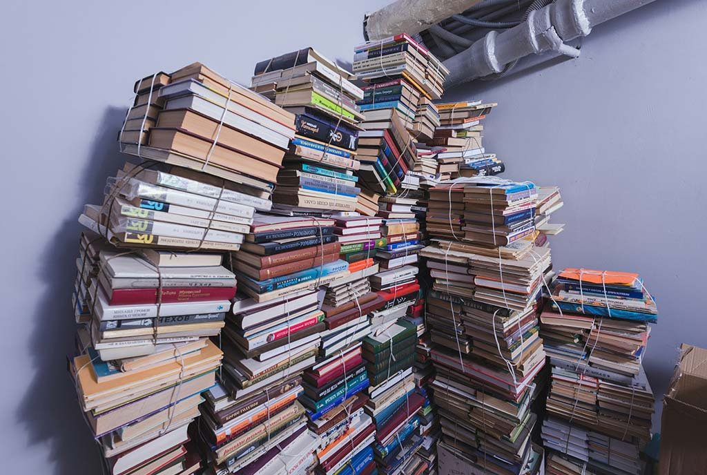 Several tall piles of tied-up books, sitting idly in an industrial room.