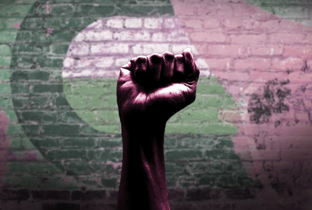 A raised fist, held up against a painted brick wall