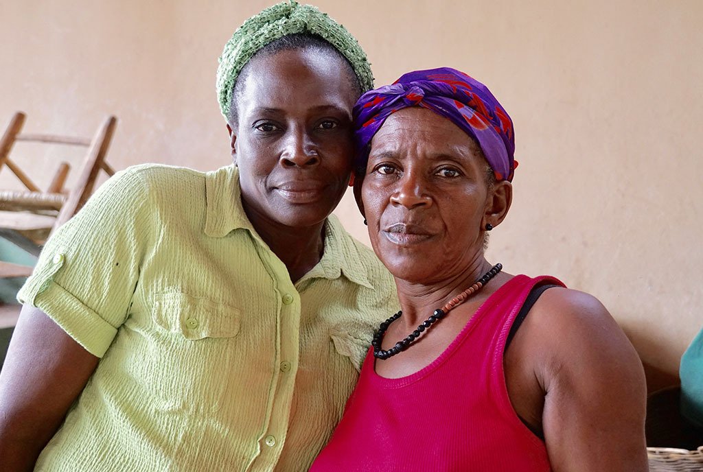 Two Haitian women standing together and looking into the camera with determined looks on their faces.