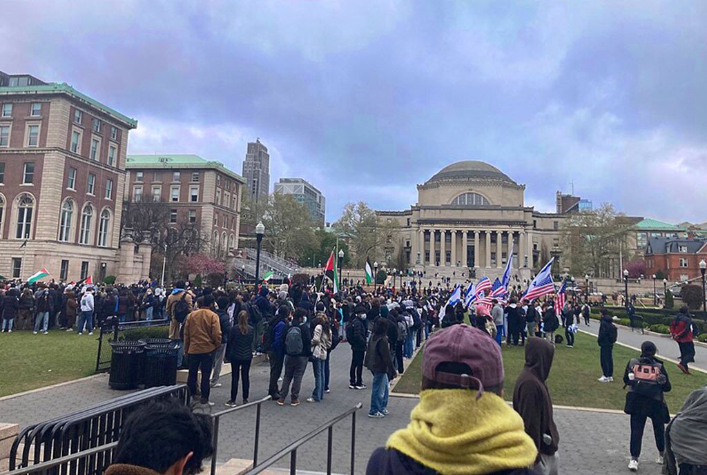 Students protesting at Columbia University on April 18, 2024. One group waves Palestinian flags and another gorup waves Israeli and United States of America flags. Low Library is in the background.