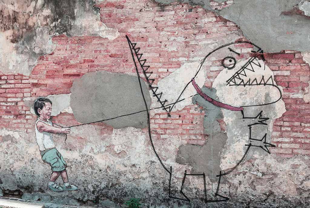 A mural of a small kid laughing while using a leash to reign in an angry cartoonish dinosaur.