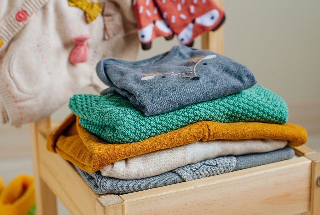 A pile of colorful children’s clothing sits in a wooden box.