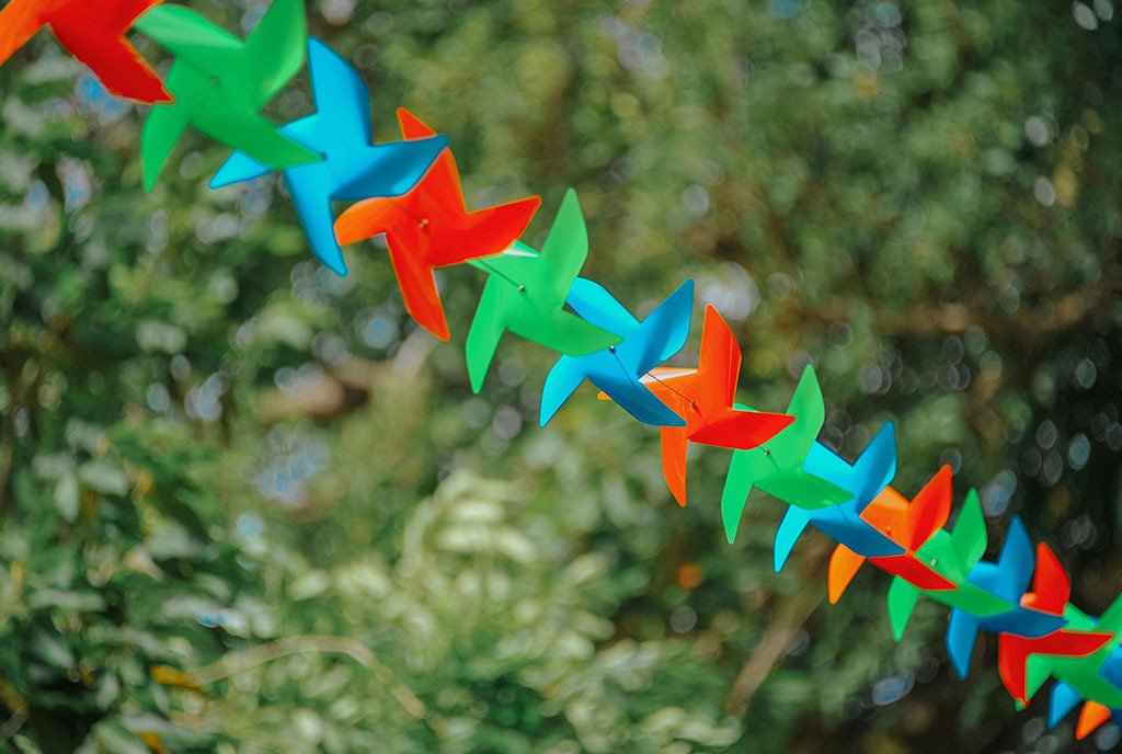 High focus image of pinwheels, strung together so each is connected to the others' movement and building on the wind of the wheel before it.