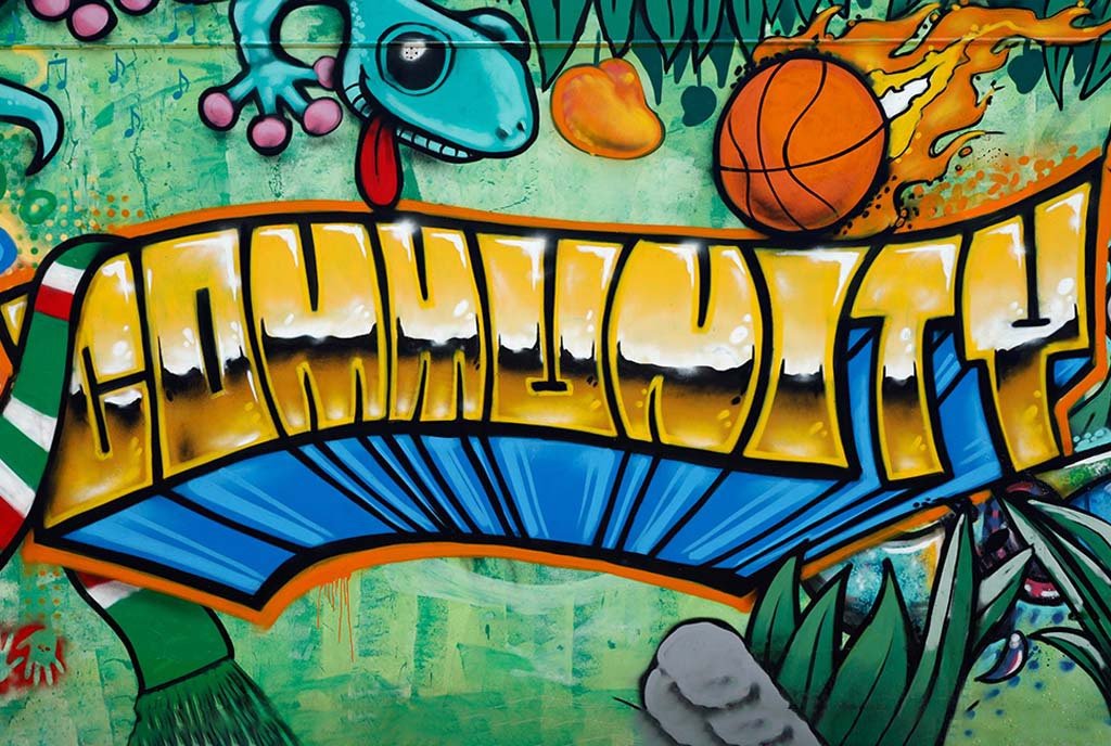 A colorful graffiti mural of the word “COMMUNITY” in shiny gold letter.