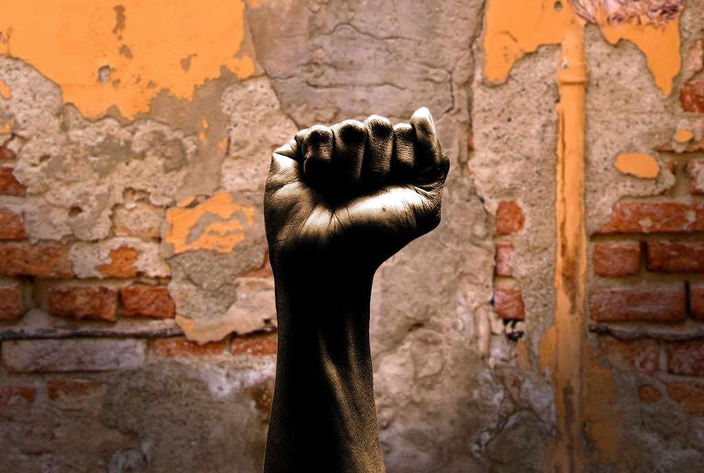 A fist raised in the air, in front of a brick wall