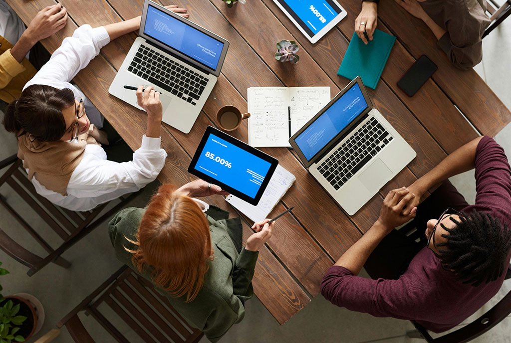 Bird’s eye view of a diverse group of workers collaborating, and discussing, to work towards a common goal