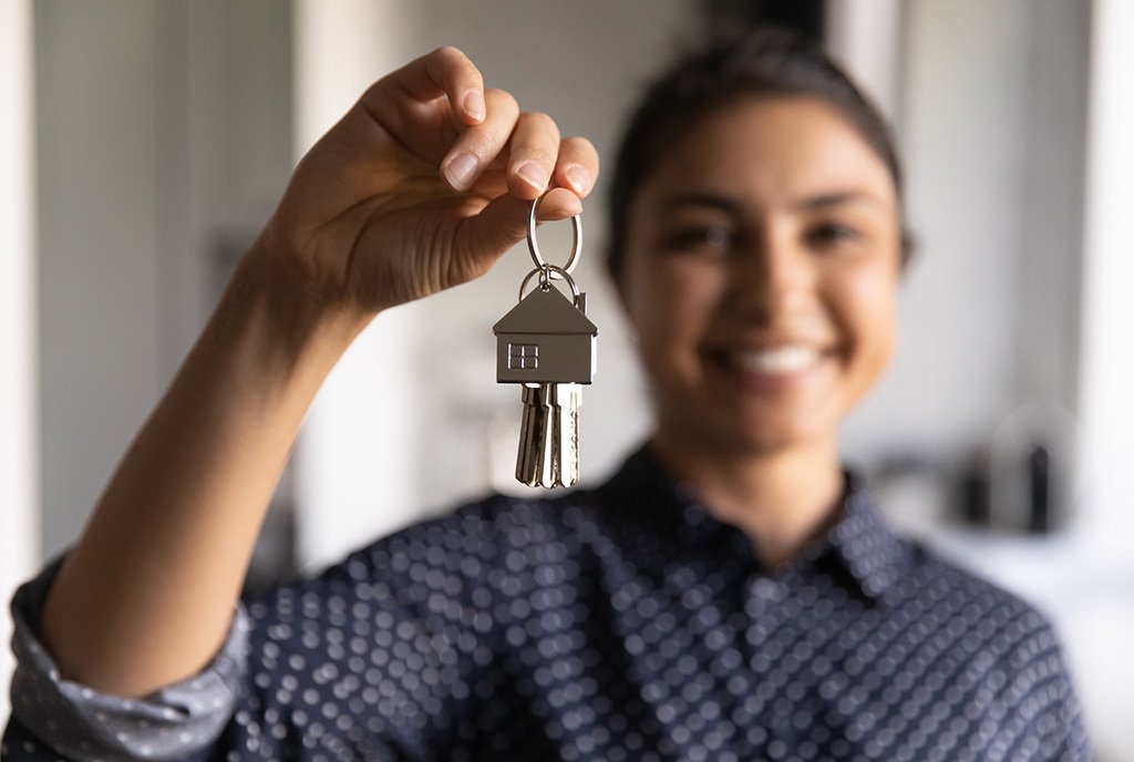 a happy brown women holding up a house key to the camera.