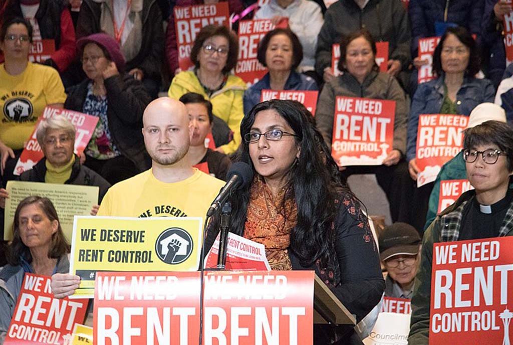 Tenants in Seattle, Washington organize at a rally to protest for rent control. The crowd is holding red signs that read, “We Need Rent Control”.