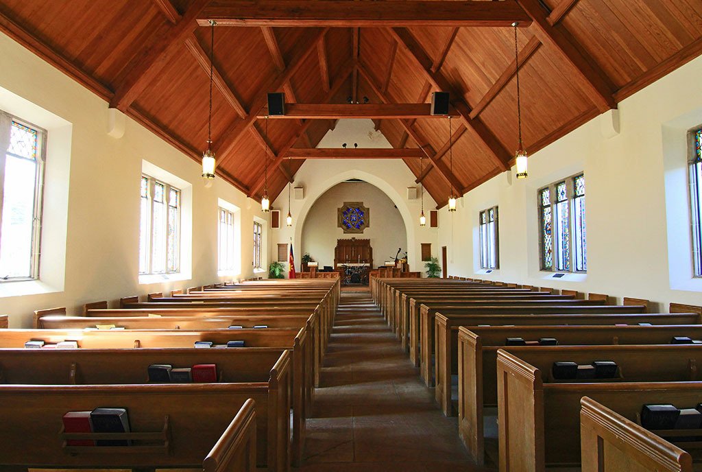 The interior of a small Louisville, KY church with pews lining either side of a central aisle.