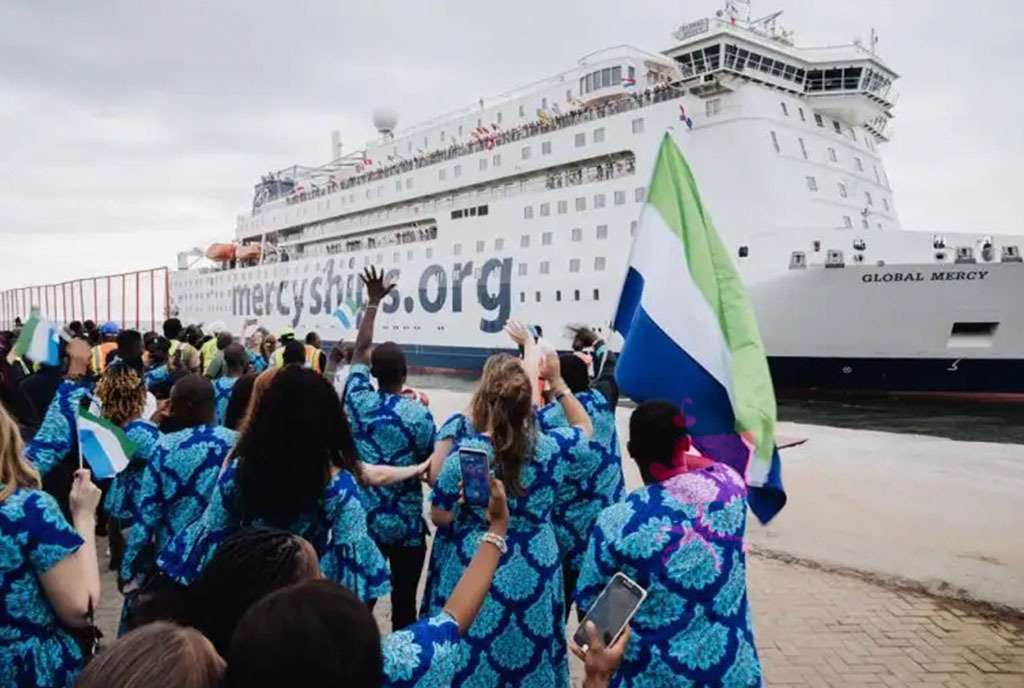 The hospital ship, Global Mercy sailing into the port of Freetown, Sierra Leone, on August 22 as many people wave and celebrate at the dock.