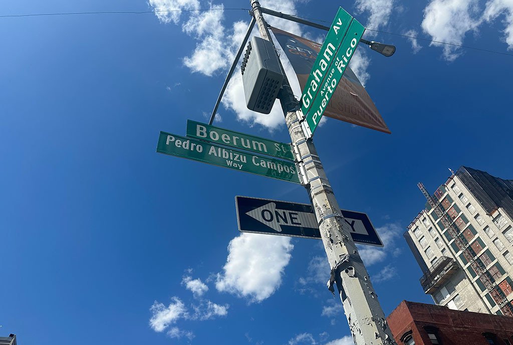 An upward look at the corner intersection street sign showing the Avenue of Puerto Rico and a street named after Pedro Albizu Campos.