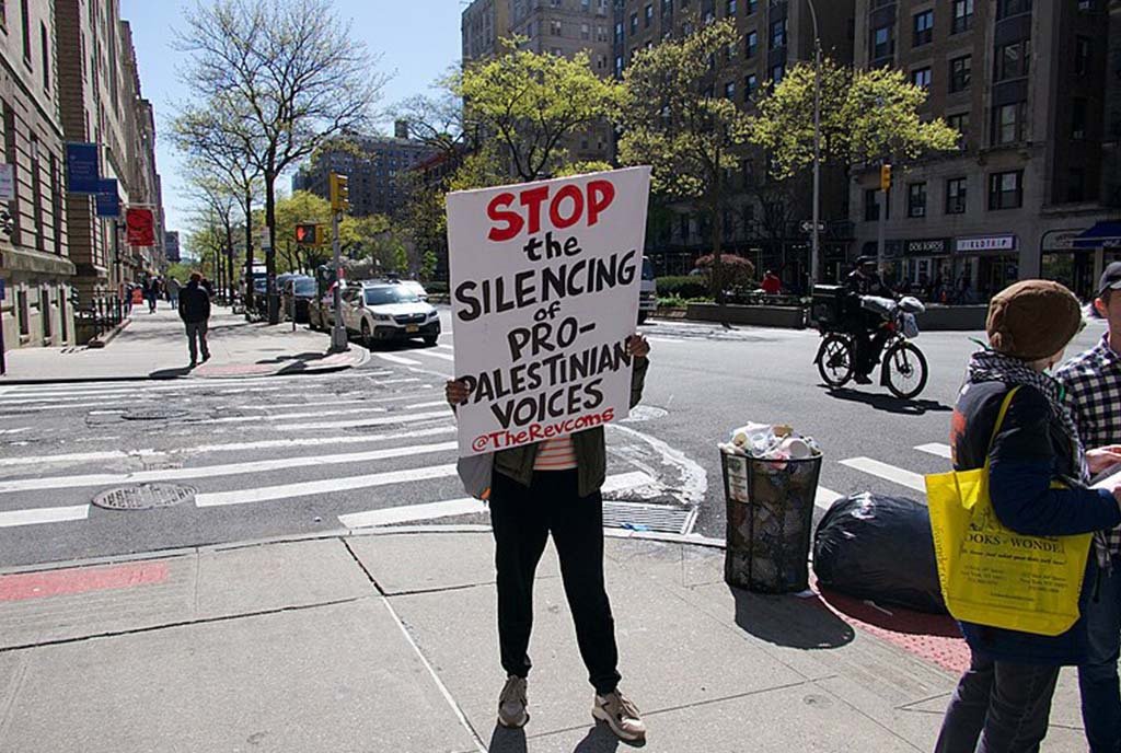 A woman holds up a sign that reads, “Stop the silencing of pro-Palestinians Voices” at Columbia University, where student protests demanding divestment from weapons companies were shut down with police enforcement.