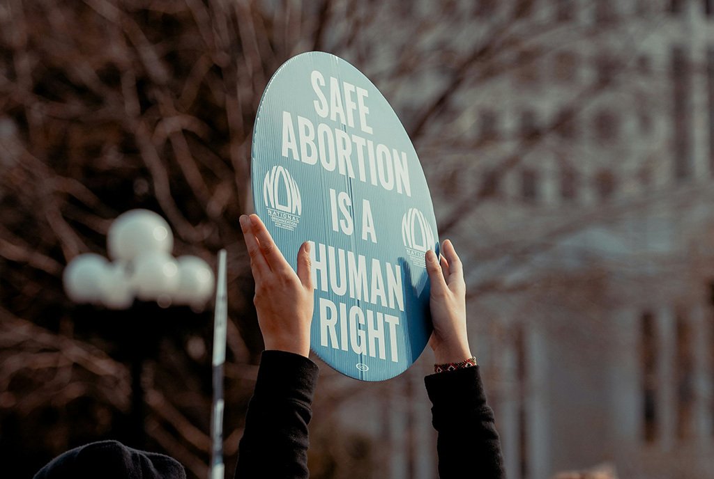 A person holding up a sign that reads, “Safe Abortion Is A Human Right”