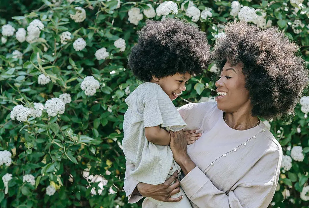 A Black mother joyfully interacting with her children, symbolizing financial and emotional stability.