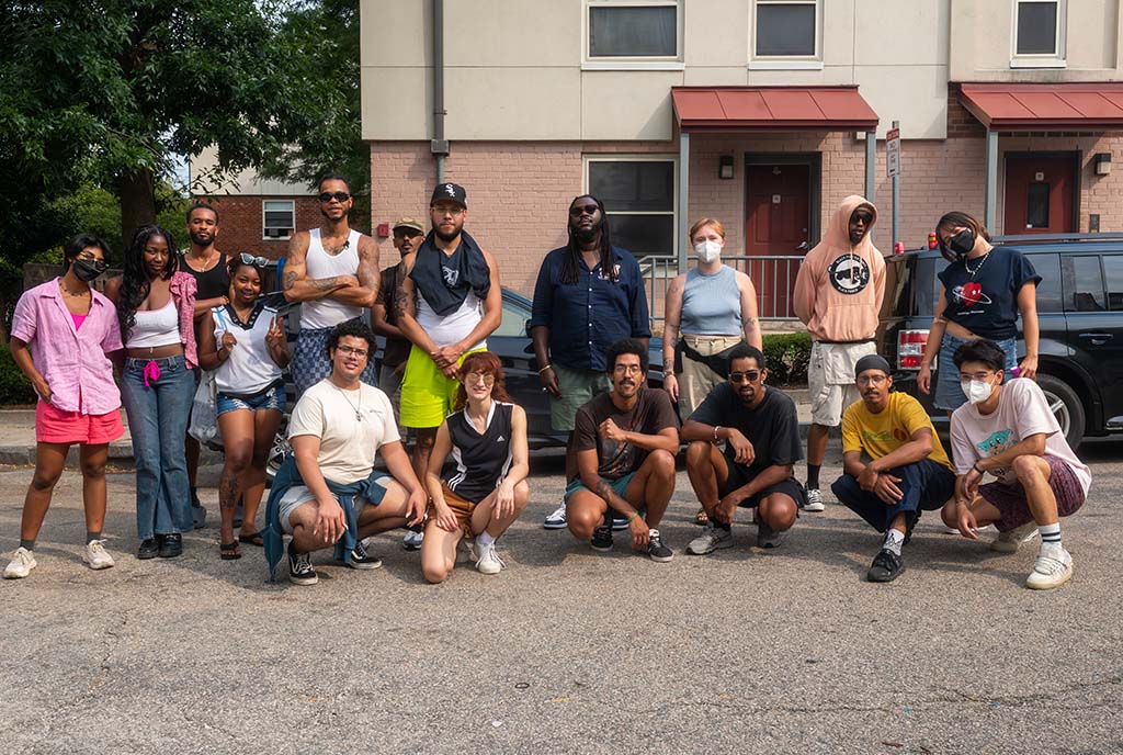 A group of volunteers and community organizers who sustain the hyper-local community program, “Heal the Hood”. They are standing together in two rows looking at the camera.